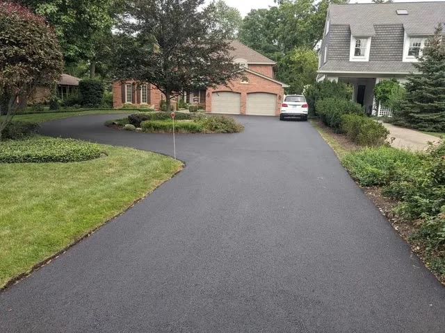 Finished asphalt driveway at a brick home with three-car garage