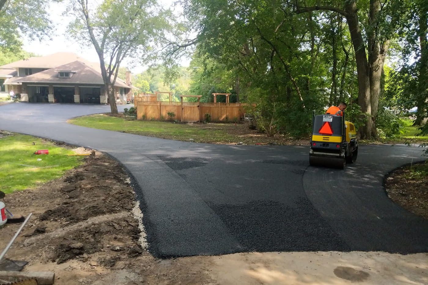 Roller working a curved fresh asphalt drive