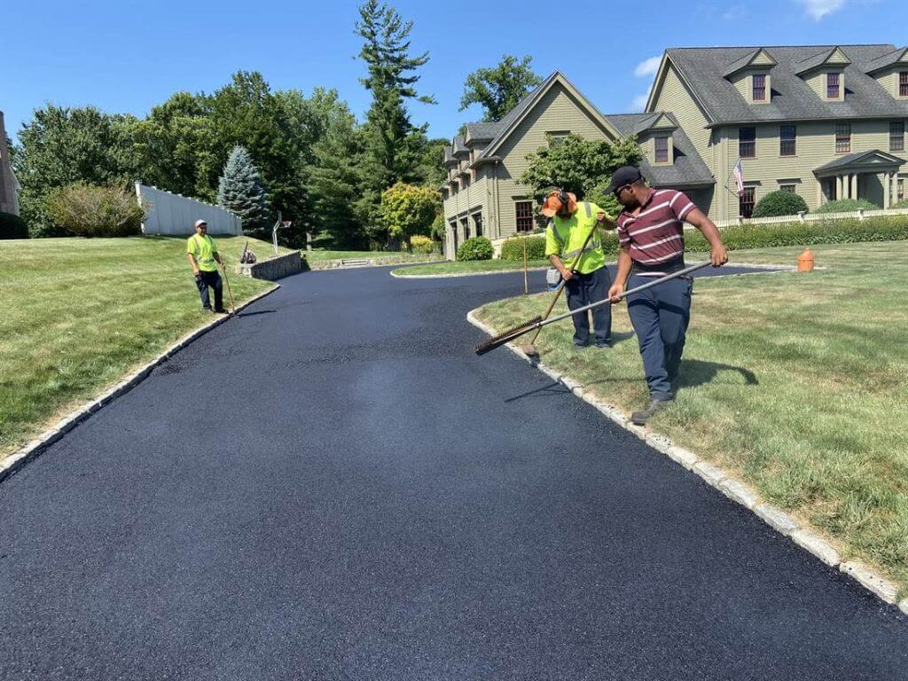 BC Paving crew raking fresh hot mix asphalt on a driveway